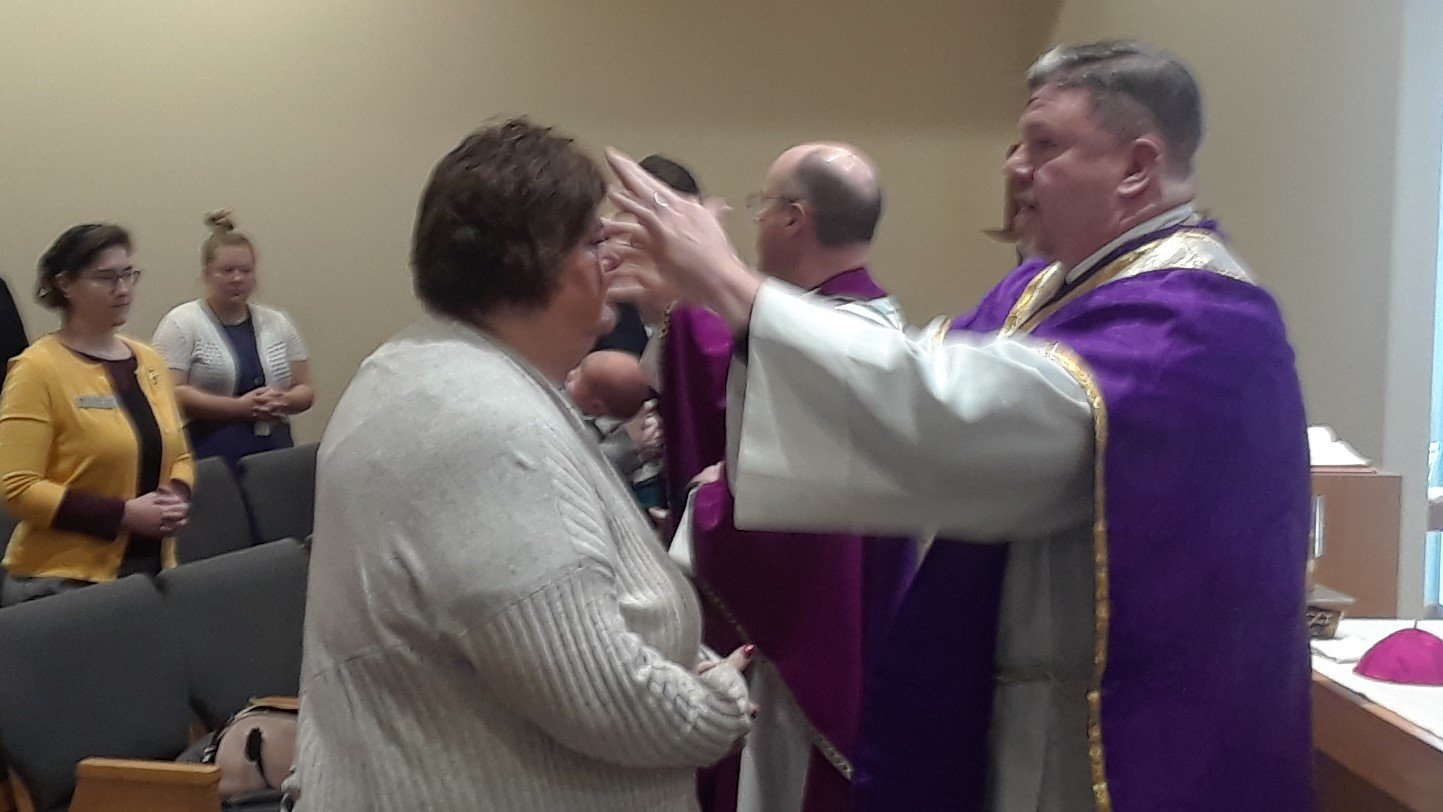 Father Stephen Jones (foreground) and Bishop W. Shawn McKnight trace ashes in the shape of a cross on the foreheads of Chancery employees the morning of Ash Wednesday at Mass in the Alphonse J. Schwartze Memorial catholic Center in Jefferson City.